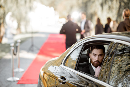 Portrait of a man as a famous movie actor sitting in the luxury car, arriving on the awards ceremony...