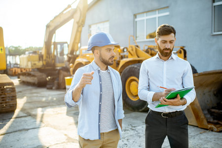 Builder choosing heavy machinery for construction with a sales consultant, signing some documents on...