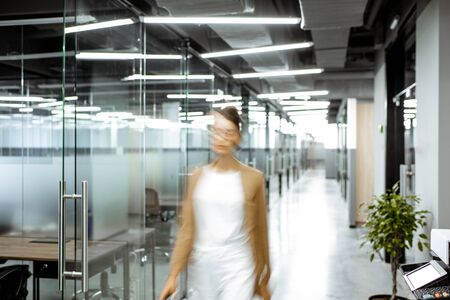 View of a modern office intreior with blurred woman figure in the hallwayの写真素材