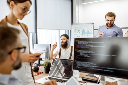 Group of diverse colleagues working on the computers in the modern office or coworking space, bearded hipster having an ideaの写真素材
