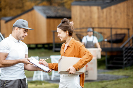 Couriers delivering goods to a young woman home by cargo van vehicle, client signing documents,...