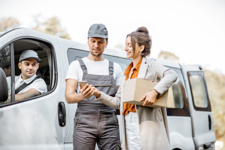 Delivery company employees in uniform delivering goods to a client by cargo van vehicle, woman...