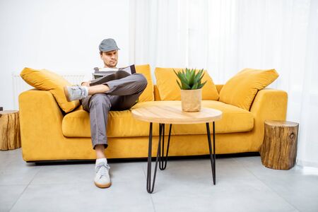 Handyman in workwear sitting on the yellow couch while resting after the workの写真素材
