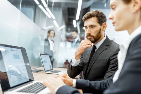 White-collar employees working on the laptop at the working place in the finance department of a large corporationの写真素材