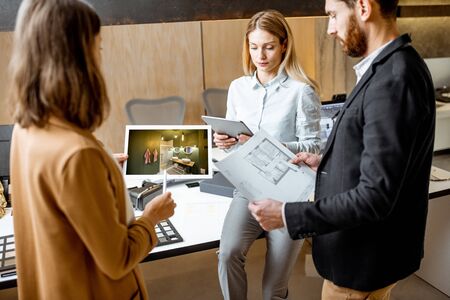 Creative office employees working on some architectural project, holding plans and interior renderings, standing in the modern office studioの写真素材