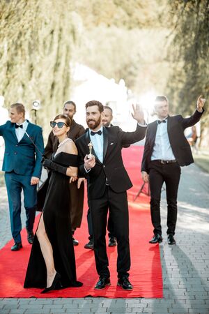 Group portrait of an elegant people as a famous movie actors standing together on the red carpet during awards ceremony outdoorsの写真素材