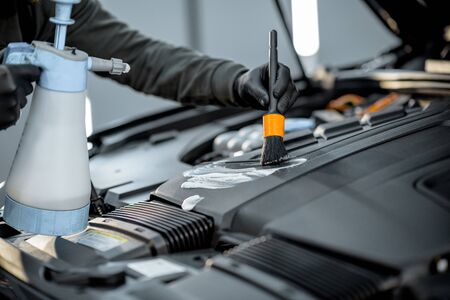 Man performs a professional car cleaning, washing engine with brush and detergent at the service station, close-up viewの写真素材
