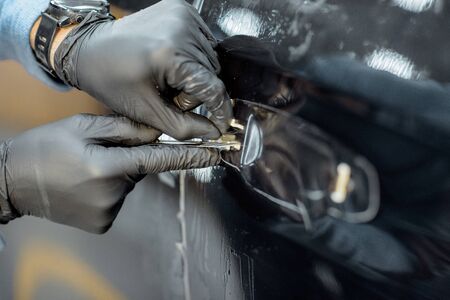 Worker sticking protective transparent film on a car body in place of the door handle, close-up viewの写真素材