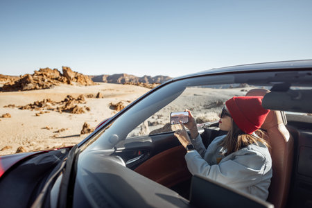 Young woman traveling by convertible car on the picturesquare road on the desert valley,...