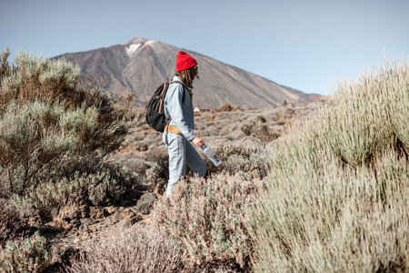Young woman in red hat traveling with backpack on the volcano valley, hiking on a Teide national park on Tenerife islandの写真素材