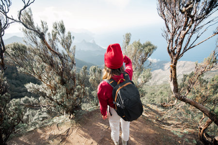 Woman in red hat enjoying breathtaking view on the rocky coastline of Tenerife island while...