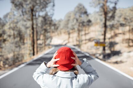Woman in red hat on the beautiful mountain road, holding her head, lost or having a problemの写真素材