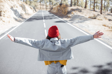 Lifestyle portrait of a stylish woman running on the beautiful mountain road, feeling happy and...