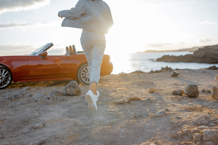 Woman running to the sea on the rocky coast, traveling by car on the island. Close-up view on female...