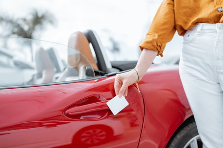 Woman opening car door with a plastic card, close-up on hands and door handle. Concept of keyless...