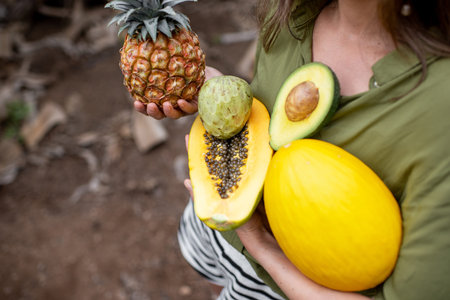 Woman with exotic food outdoors, closeup on ananas, papaya, melon, avocado and cherymoya fruits....