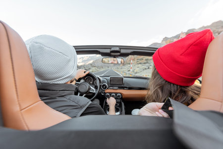 Couple driving a cabriolet on the mountain road, traveling by car and enjoying vacations, view from...