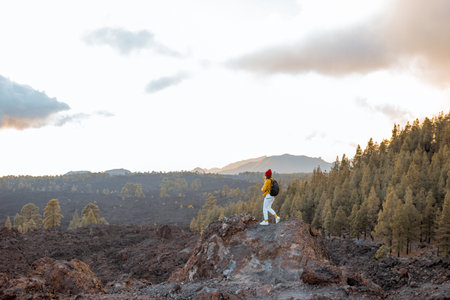 Volcanic landscapes on a sunset, woman walking on the rocky land while traveling on the islandの写真素材