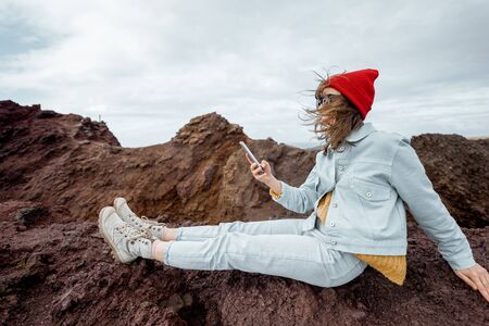 Young traveler resting on the rocky land, traveling volcanic landscapes on the ocean shore near the lighthouseの写真素材
