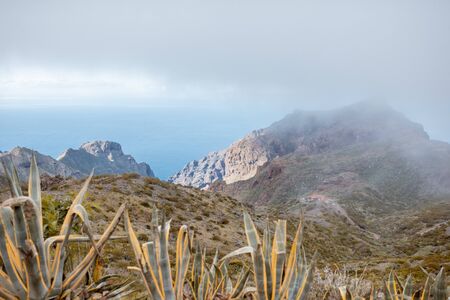 Beautiful landscape on a rocky mountain with the ocean on the background under the clouds, Tenerife island, Spainの写真素材