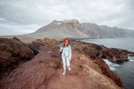 Young traveler walking on the rocky ocean shore, beautiful landscape view on Tenerife island, Spain. Concept of a carefree travel and adventuresの写真素材