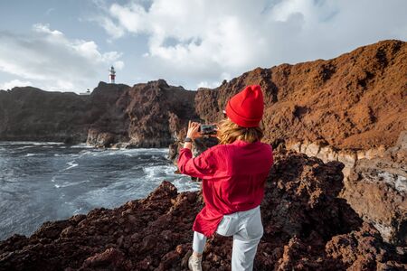 Woman photographing on phone great views on the rocky ocean coast, traveling on the Teno cape on the Tenerife island, Spainの写真素材