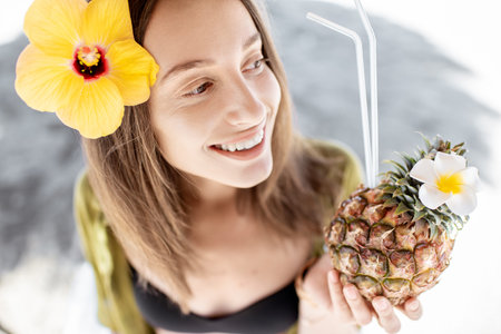 Portrait of a beautiful young smiling woman with exotic cocktail at the beach resort on a sunny day....