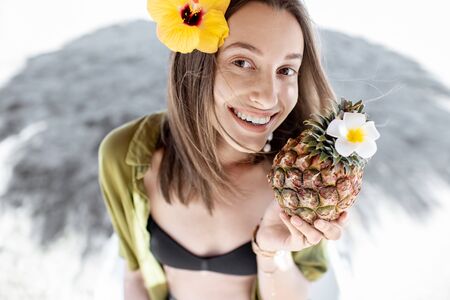 Portrait of a beautiful young smiling woman with exotic cocktail at the beach resort on a sunny day. Concept of exotic summer vacations, beauty and wellnessの写真素材