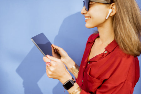 Image of a young woman with a digital tablet and wireless earphones on the violet background....