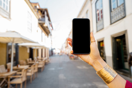 Woman holding smart phone with black screen to copy paste on the old city street, close-up on phone