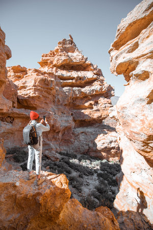 Female traveler enjoying beautiful landscapes standing between the huge rocks volcanic origin on a...