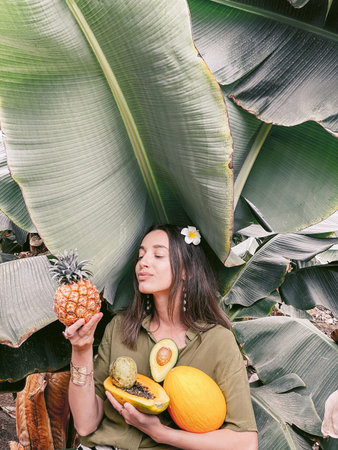 Portrait of a young smiling woman with exotic food in banana leaves. Image made on mobile phone