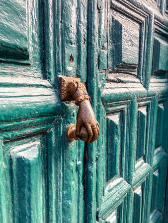 Retro door handle on the green ancient door. Image made on mobile phone
