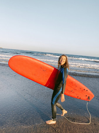 Young surfer walking with surfboard on the beach. Image made on mobile phone