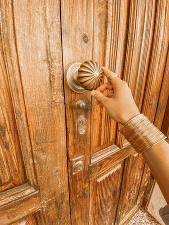 Woman holding retro door handle on the ancient wooden door. Image made on mobile phoneの写真素材