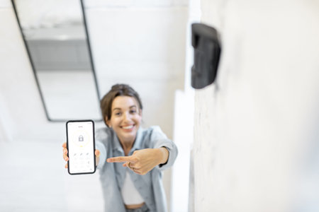 Woman controlling alarm system with a smart phone, showing phone with launched mobile application....