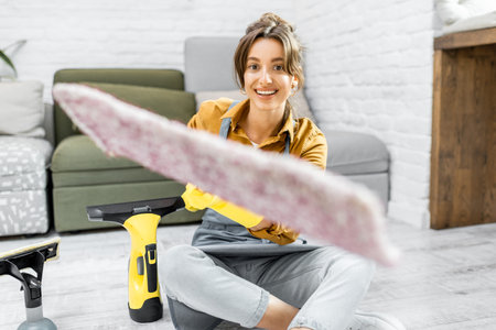 Portrait of a joyful woman as a housewife, pushing forward mop, while cleaning at home