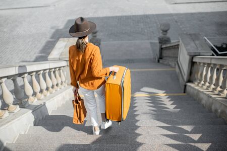 Young female traveler walking down the stairs with a suitcase, traveling in the old cityの写真素材