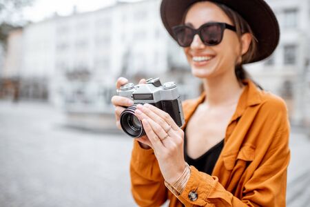 Portrait of a young stylish woman with photo camera traveling old city street. Concept of happy traveling and summer vacations in the european townの写真素材