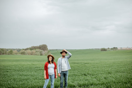Portrait of a lovely couple standing together on the greenfield. Happy couple expecting a baby,...