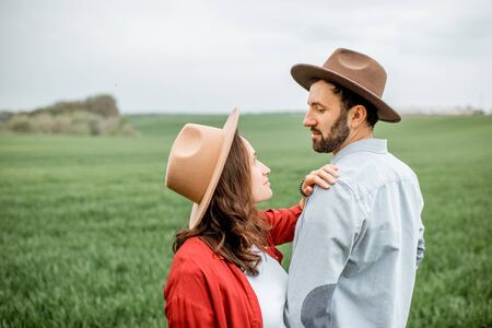 Portrait of a lovely couple standing together on the greenfield. Happy couple expecting a baby, young family conceptの写真素材