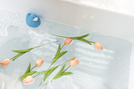 Bathtube full of water with flowers and rubber duck at home