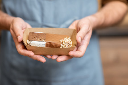 Seller holding chocolate ice cream on a cardboard, close-up