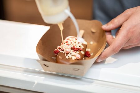 Seller making chocolate ice cream with toppings at the shop, close-upの写真素材
