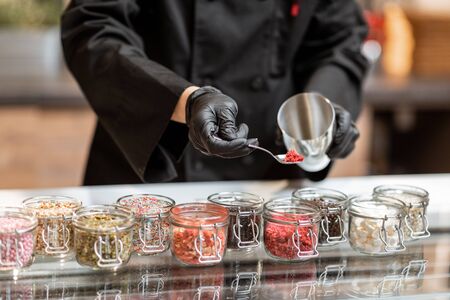 Chef mixing different ice cream toppings for sprinkling on the chocolate ice cream at the shop, close-upの写真素材