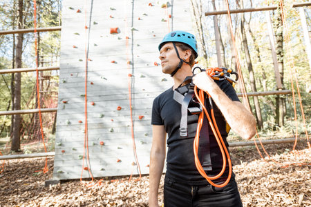 Handsome man well equipped with protective climbing equipment standing at amusement park outdoors