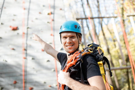 Portrait of a happy man well equipped with protective climbing equipment at amusement park outdoors