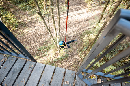 Man jumping from a bungee tower, having an active recreation in a rope park in the forest