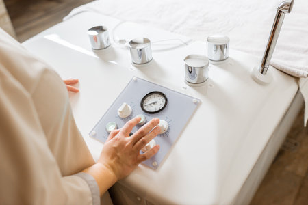 Spa worker presses buttons during procedure in balneology with carbon dioxide bath, close-upの写真素材