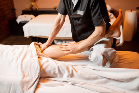 Professional therapist doing a deep massage to a male client at Spa salon. working on the lower bodyの写真素材